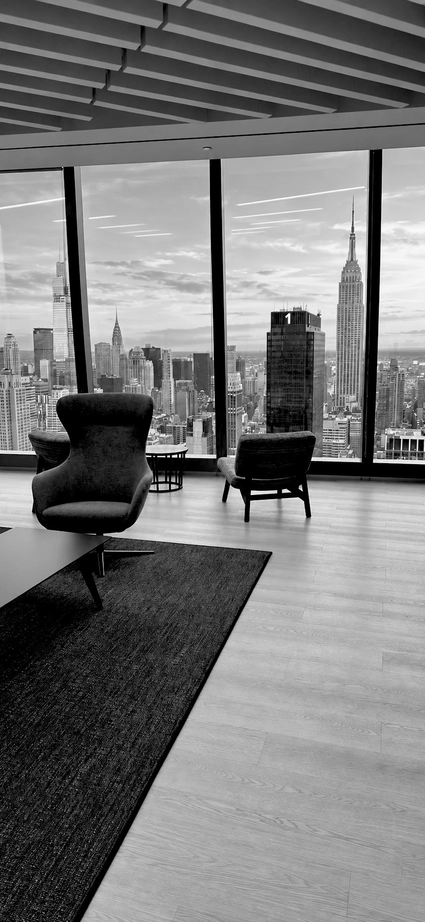 A quiet office lounge high above Manhattan, with the Empire State Building outside the windows
